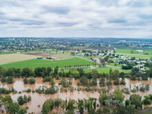 Flooding River Full Of Brown Floodwater With Farm Paddocks