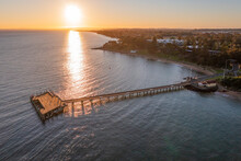 Aerial View Of A Sunrise Over A Long Straight Jetty Leading Out To A Platform