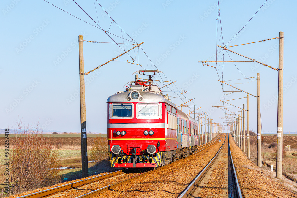 Red Intercity Train A red electric locomotive pulls the carriages of a high-speed intercity ...
