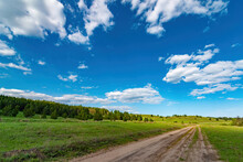 Dirt Road Rural Countryside Leading To The Top Of The Hill, Blue Dramatic Storm Clouds At Summertime