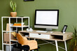© Seventyfour - Background image of home workplace with blank computer on wooden table against green wall, copy space