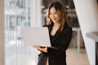 © Kritdanai - Asian businesswoman in formal suit in office happy and cheerful during using smartphone and working