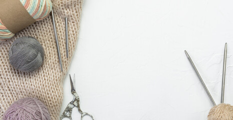 knitted beige sweater, knitting yarn, knitting needles and crochet hooks on a light background. copy
