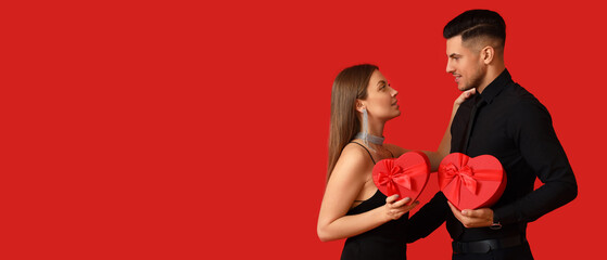 Poster - Happy young couple with gifts on red background. Banner for Valentine's Day