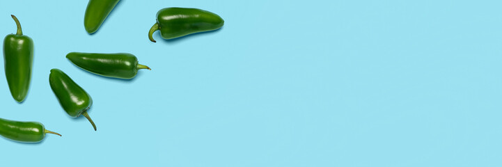 Green jalapeno peppers on light blue background with space for text, top view