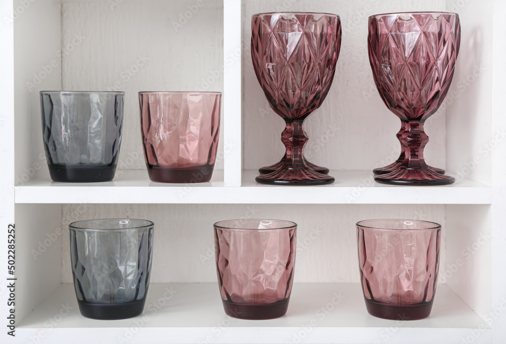 Empty stylish glasses on shelf unit, closeup