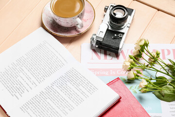 Wall Mural - Books, cup of coffee, newspaper, flowers and photo camera on light wooden background