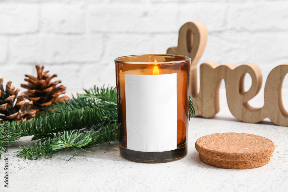 Holder with burning candle and fir branch on table, closeup