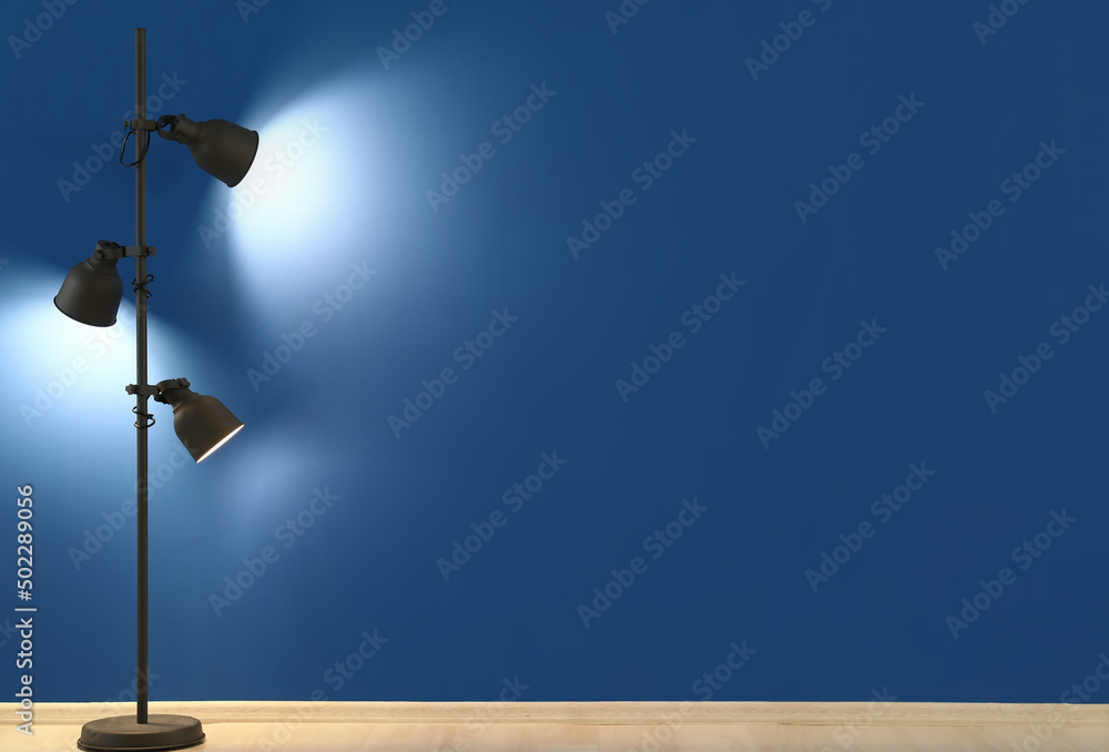 Glowing standard lamp near blue wall