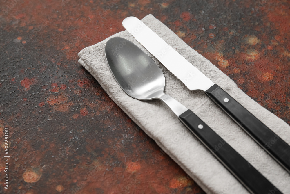 Spoon, knife and napkin on grunge background