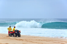 Ocean Lifeguards Patrolling The Beach On An ATV Under Heavy Surf Looking For Swimmers In Distress On The Northshore Of Oahu In Hawaii