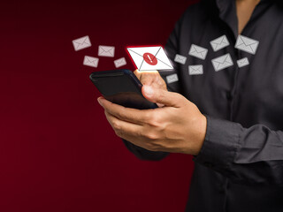 Wall Mural - businessman holding a smartphone receives a new message with email icons while standing on a red bac