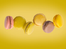 French Pastries - Macaroons On A Bright Yellow Background In Frozen Flight. Beautiful Composition. Holiday, Birthday. Advertising, Banner, Invitation. There Are No People In The Photo.