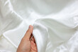 Hands touch the white cloth that is shiny. Good fabric. Selection of linen fabric.