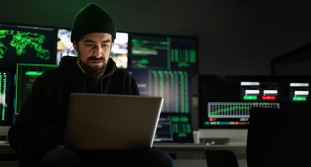 Horizontal banner. Hacker hacking security firewall in basement hideout. Multiple screens background. Copy space.