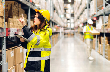 Asian two engineer team shipping order detail on tablet check goods and supplies on shelves with goods background inventory in factory warehouse.logistic industry and business export