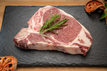 Wall Mural - T-bone steak beef on black plate. Fresh T-bone steak beef with rosemary on wooden background, 