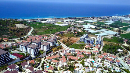 Top view of agricultural city by sea. Stock footage. Agricultural fields with greenhouses are located in city on coast of blue sea. Beautiful landscape of southern modern city with agriculture