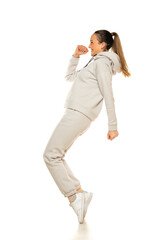 Wall Mural - a young woman in a gray tracksuit poses against a white background in the studio