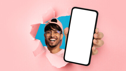 Indian guy showing white empty smartphone screen through torn paper