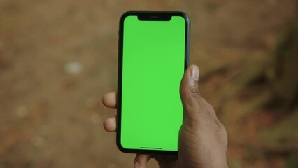 close-up of the hand of a black man with a mobile phone with a green screen