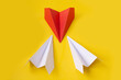 Red paper plane changing direction from white paper plane on yellow background. business concept for new ideas creativity
