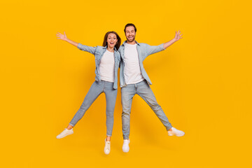 Wall Mural - Full length body size view of attractive cheery funny people jumping having fun isolated over bright yellow color background