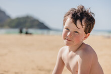 Happy Boy On Sandy Beach Looking At Camera