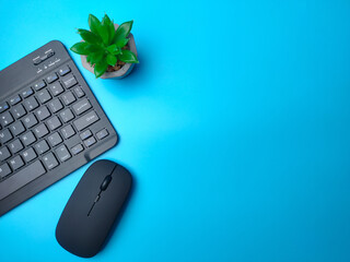 Malaysia,30 April 2022: Black Bluetooth wireless keyboard and wireless mouse with green plant on a wooden background with copy space.