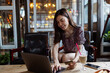 © Алина Бузунова - Pretty young asian business woman using laptop in modern cafe.