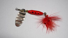Closeup Of Bait For Fishing In The Shape Of A Spoon With A Red Fluff On A White Background