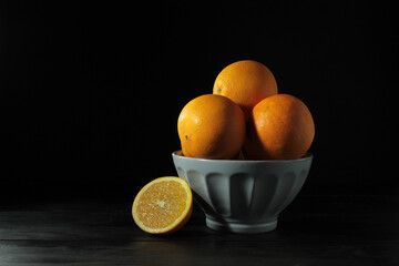 Poster - Closeup shot of oranges on a white bowl against a black background