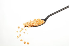 Falling Yellow Peas Grains From A Black Spoon On A White Background. Shallow Depth Of Field