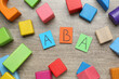 Colorful building blocks and cards with abbreviation ABA on wooden table, flat lay