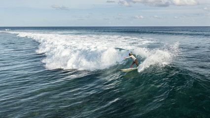 Sticker - Aerial view of a female surfer riding the huge waves