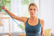 © gzorgz - Attractive woman exercising with a power band at home