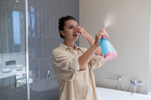 A Young Woman Closing Her Nose From Unpleasant Smell And Spraying Air Freshener