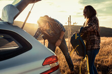 Couple Preparing For A Hiking As They Taking Their Backpacks Out Of The Trunk Of The Car.