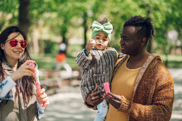 Multiracial family blowing soap bubbles in park