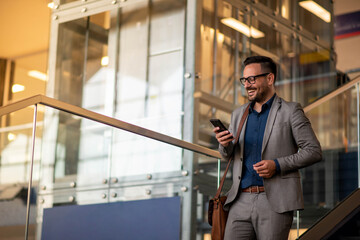 Wall Mural - A businessman talking on a cell phone in front of the modern building.