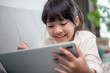 © FAMILY STOCK - Little girl using tablet playing game on the internet, Kid sitting on sofa watching or talking with a friend online, Child relaxing in living room in the morning, Children with New Technology concept