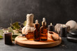 © Pixel-Shot - Wooden board with bottles of essential oil, sea salt, massage bag and burning candles on dark background