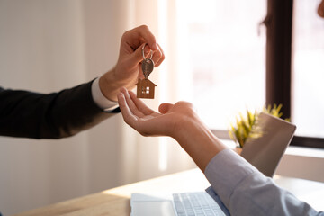 The real estate broker sends the house keys to the client after signing the contract with insurance. Mortgage, rent, buy, sell, move home concept.