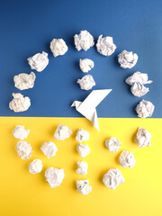 Wall Mural - Peace symbol of crumpled paper balls with an origami dove on blue and yellow paper as Ukrainian flag