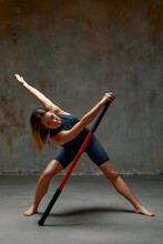 Beautiful Girl In Sports Uniform Is Training Kung Fu In The Studio, Fighter Athlete, Practicing Martial Arts With A Stick