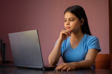 Wall Mural - Portrait of a beautiful and young Indian woman working on her laptop