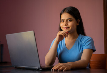 Wall Mural - Portrait of a beautiful and young Indian woman working on her laptop