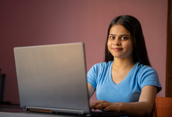 Wall Mural - Portrait of a beautiful and young Indian woman working on her laptop