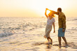 Young romantic couple dancing turning around by sea. Seascape at sunset with beautiful sky. Romantic couple on the beach at golden sunset. Lover couple having fun on beach.