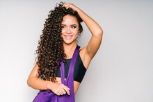 An Energetic And Happy Cheerleader With Dark Curly Hair In A Black Sports Top And A Purple T-shirt Looks To The Left. The Girl Holds Her Hair On Her Head With Her Right Hand, And Puts Her Left Hand On
